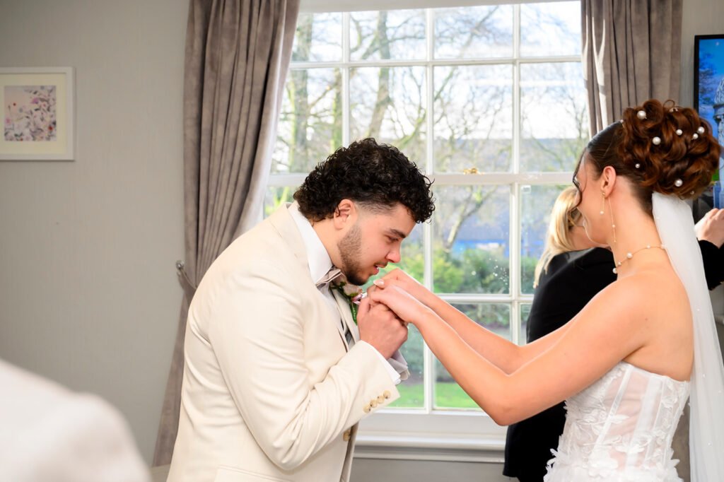 Groom kissing bride's hand during wedding ceremony.